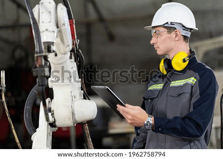 Male engineer worker using digital tablet for control automatic robotic arm machine in the factor