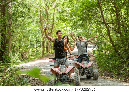Group of young man and woman driving off road adventure with happy and smiling. Friends riding on ATV bike or quad bike on road along forest trail on mountain. Camping, jungle adventure concept
