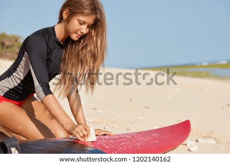 Image, Stock Photo Crop female surfer waxing surfboard with basecoat