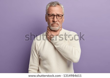Its hard to swallow. Senior mature man has thore throat, feels sick, has fever, quiet voice, wears spectacles and white jumper, isolated over purple background. People and problems with health