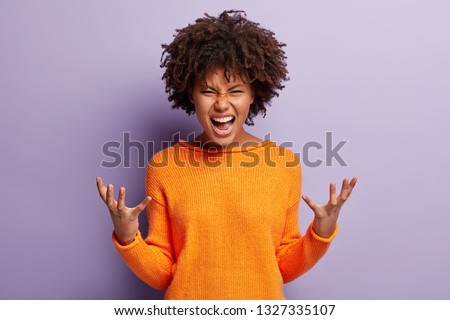 Angry annoyed female gestures with annoyance, screams loudly, expresses irritation, wears casual orange jumper, reproaches partner in betrayal, isolated over purple studio wall. Stop it please Сток-фото © 