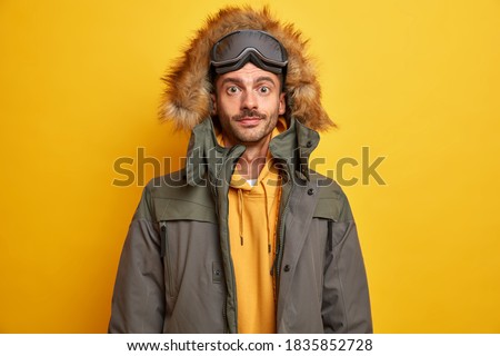 Sérieux homme non-rasé se reposer en hiver en montagne et aime faire du snowboard habillé d