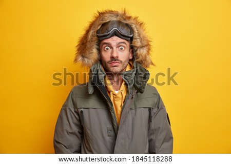 Photo de jeune homme surpris avec des lunettes de snowboard fixes les yeux fixés par les yeux obsédés par un blizzard orageux vêtu de vêtements de sport d