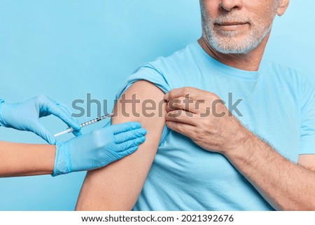 Faceless doctor makes covid 19 vaccine injection to elderly patient wears protective rubber gloves. Unknown senior male model being immunized against coronavirus. Medical treatment against pandemic