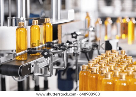 Production line of beauty and healthcare products at plant or factory. Process of manufacturing and packaging cosmetics goods. Glass or plastic bottles with screw caps standing on conveyor belt