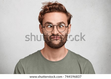 Funny comic man crosses eyes, pouts lips, makes grimace, foolishes after all day studying. Clueless male nerd with awkward expression has fun alone, plays fool, isolated over white background Сток-фото © 