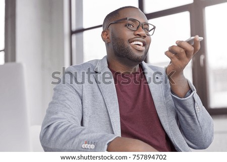 Attractive black male enterpreneur makes voice call for consulting about cash remittance, uses modern smart phone. Successful businessman discusses something with colleague via modern smart phone