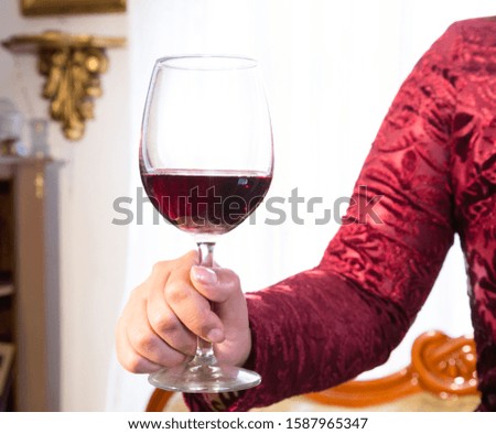 glass of red wine held by a woman's hand on white background