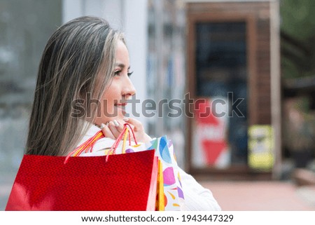 A closeup portrait of an elegant happy Hispanic woman holding shopping bags over her shoulder