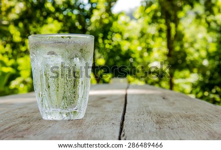 Glass of cold water shooting range Place the left side on a wooden table Focus on water drops on glass.