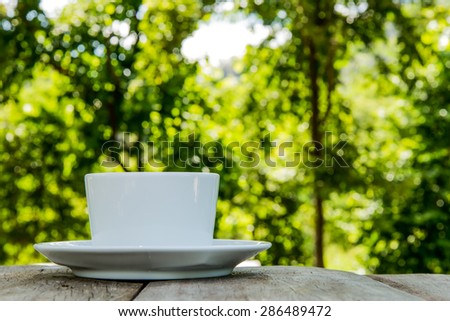 White left the coffee cup on a wooden table. Focus on the top edge of the glass.