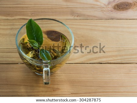 Tea and fresh tea leaves in the cup. Taking place on the top floor, light wood, focus on the tea leaves.