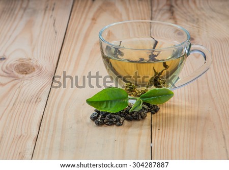 Tea, tea leaves, fresh and dried tea place right on the light wood of focus leaves and glass.