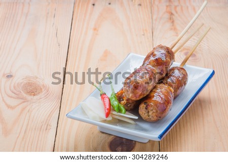 Thailand style sausage and chili on a plate placed on a wooden floor and white sausage focus.