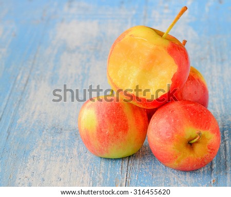 Four red apples place on blue wooden floor. focus front and bite marks.