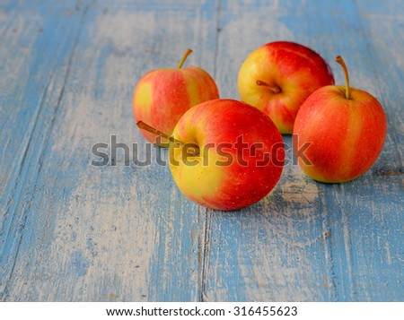 Four red apples place on blue wooden floor,front focus.