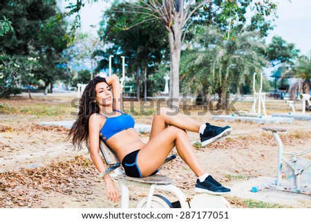 Brunette with long hair in shorts and a short t-shirt  in the gym outdoors