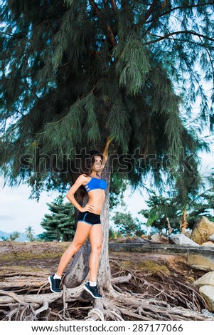 Brunette enjoys sports outdoors in short black shorts and a blue t-shirt