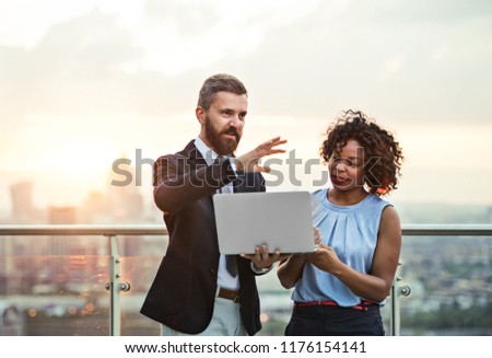 Un retrato de empresarios con un portátil parado en contra de la puesta de sol de Londres.