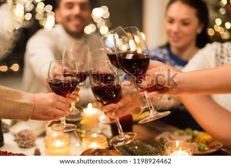 férias e conceito de celebração - fechar amigos felizes tendo jantar de Natal em casa, beber vinho tinto e copos de tilintar