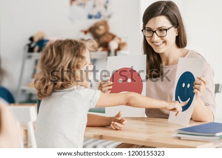 Similar – Image, Stock Photo Boy with Autism communicating with ipad while eating a homemade gluten free muffin; plastic animal toys nearby