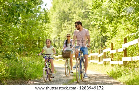 concepto de familia, ocio y gente - madre feliz, padre e hija pequeña en bicicleta en el parque de verano