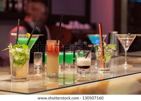 Barman serving colorful cocktails in a hotel bar.
