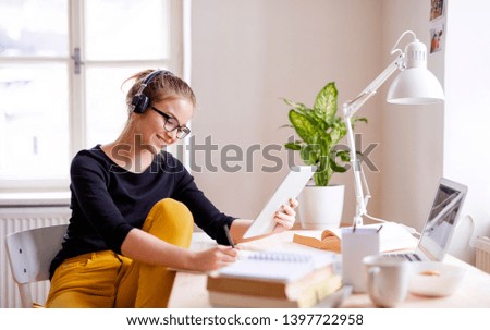 Similar – Image, Stock Photo Student learning in university library. Young woman writing essay and making notes using computer tablet. Focused student studying for college exams