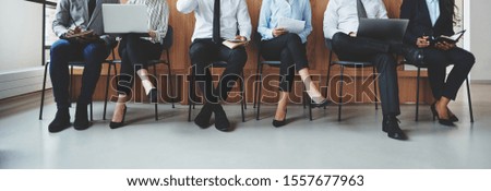 Unrecognizable group of diverse businesspeople sitting in chairs in an office reception waiting to be interviewed