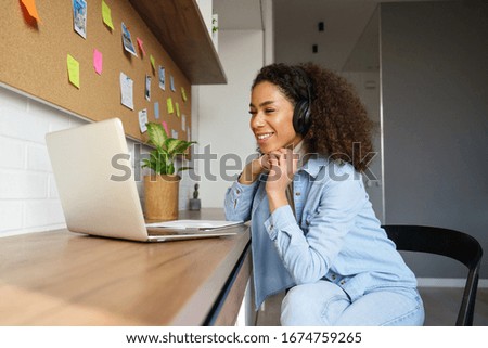Smiling young african american teen girl wear headphones video calling on laptop. Happy mixed race pretty woman student looking at computer screen watching webinar or doing video chat by webcam. Foto d'archivio © 