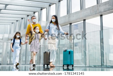 Familia con dos hijos de vacaciones, con máscaras en el aeropuerto.