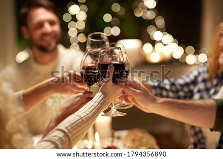 vacances, célébration et concept de personnes - amis heureux qui dînent à la maison pour noël boire du vin rouge non alcoolisé