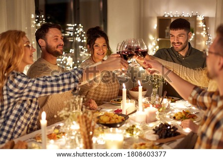 vacaciones, celebración y concepto de la gente - amigos felices cenando navidad en casa bebiendo vino tinto no alcohólico