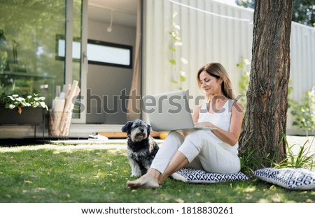Mujer madura trabajando en oficina en casa al aire libre en el jardín, usando laptop.