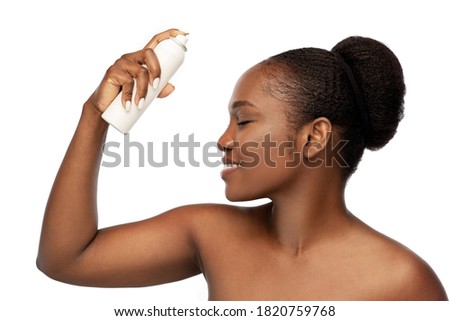 beauty, bodycare and people concept - beautiful young african woman spraying facial mist on her face skin over grey background