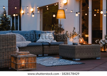 Velada de verano en el patio de una hermosa casa suburbana con luces en el jardín