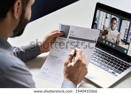 Male indian hr, recruiter or employer holding cv having online virtual job interview meeting with african candidate on video call. Distance remote recruitment conference chat. Over shoulder view. Stock foto © 