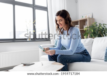 business, finances, income and people concept - happy smiling woman with calculator and bills counting money at home Foto stock © 