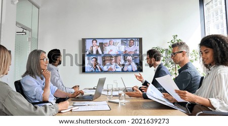 Diversos empleados de la empresa tienen videollamadas de conferencia de negocios en línea en pantalla de televisión en la sala de reuniones de la junta. Presentación en videoconferencia, concepto de formación corporativa de grupos virtuales globales.