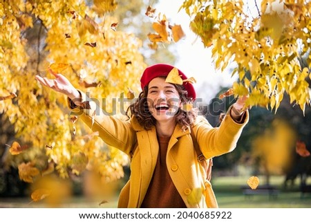 Belle jeune femme jetant des feuilles jaunes d