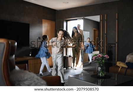Alegre familia joven con dos niños entrando en habitación en un hotel de lujo, vacaciones de verano.
