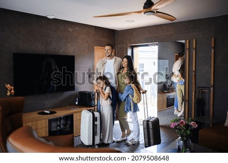 Alegre familia joven con dos niños entrando en habitación en un hotel de lujo, vacaciones de verano.