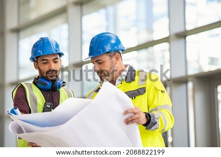 Indian architect and mature supervisor meeting at construction site. Multiethnic manual worker and engineer discussing on plan. Two construction workers working together while visiting a new building. Stockfoto © 