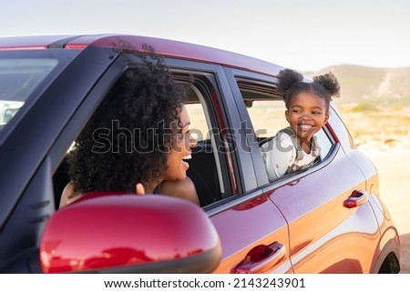 Cheerful little african american daughter sitting on back seat of car looking at mother from mirror while travelling. Young fun woman with cheerful female kid enjoying road trip.  Traveling in car. Photo stock © 