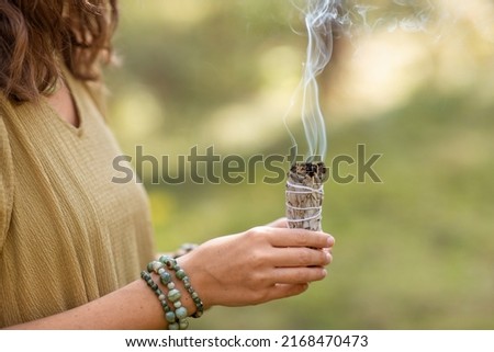 occult science and supernatural concept - close up of woman or witch with smoking white sage performing magic ritual in forest Stock fotó © 