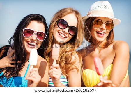 vacaciones y vacaciones de verano - chicas en bikini comiendo helados en la playa
