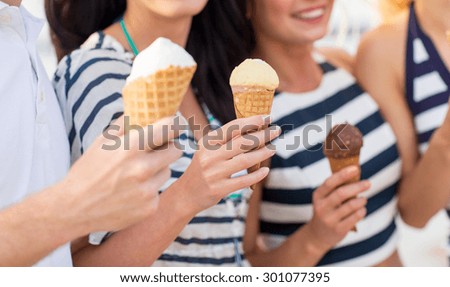 friendship, leisure, sweets, summer and people concept - close up of happy friends eating ice cream outdoors