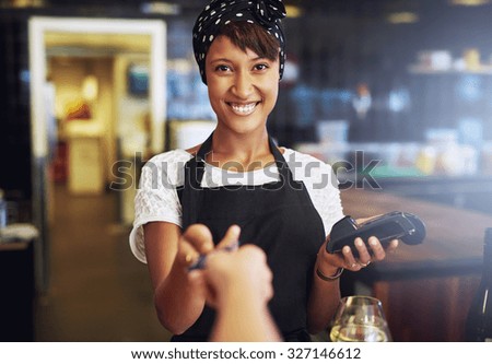 Smiling waitress or small business owner taking a credit card from a customer to process through the banking machine in payment for an order