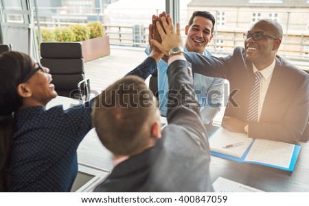 Exultant team of multiracial young business professionals rejoicing and congratulating each other giving a high fives gesture