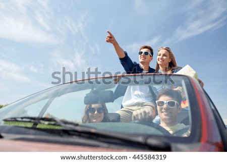 ocio, viaje por carretera, viajes y concepto de personas - amigos felices con el mapa conduciendo en coche cabriolet a lo largo de la carretera rural y señalando con el dedo a algo por delante